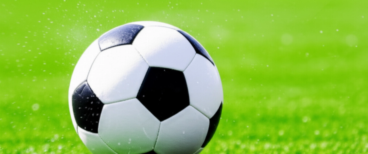 Primo piano iperrealistico di un pallone da calcio calciato da un giocatore caucasico su un campo verde, enfatizzando la qualità del prodotto.